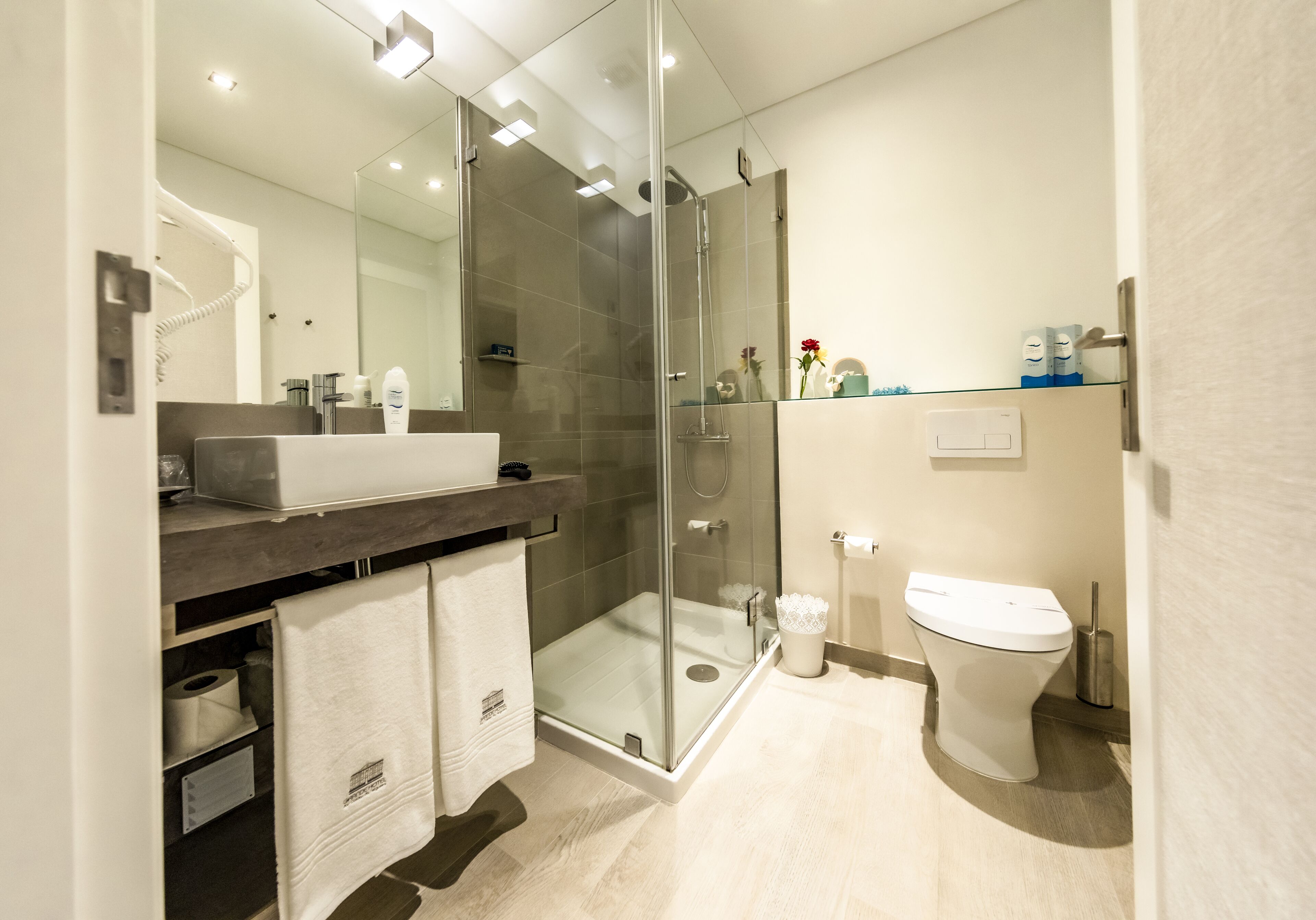 Un baño moderno con ducha de vidrio, lavamanos blanco y retrete.