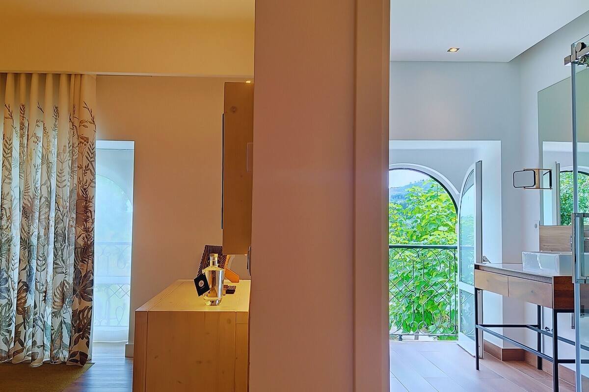 Une salle de bain moderne dotée d’une douche à parois de verre et offrant une vue sur la verdure environnante.