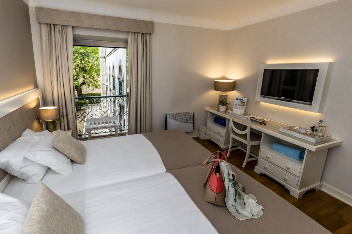 Une chambre d’hôtel avec un lit, un bureau, une télévision, une lampe et une vue sur l’extérieur.
