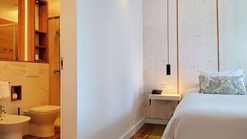Quarto de hotel com cama, mesa de cabeceira e guarda-roupa de madeira.
