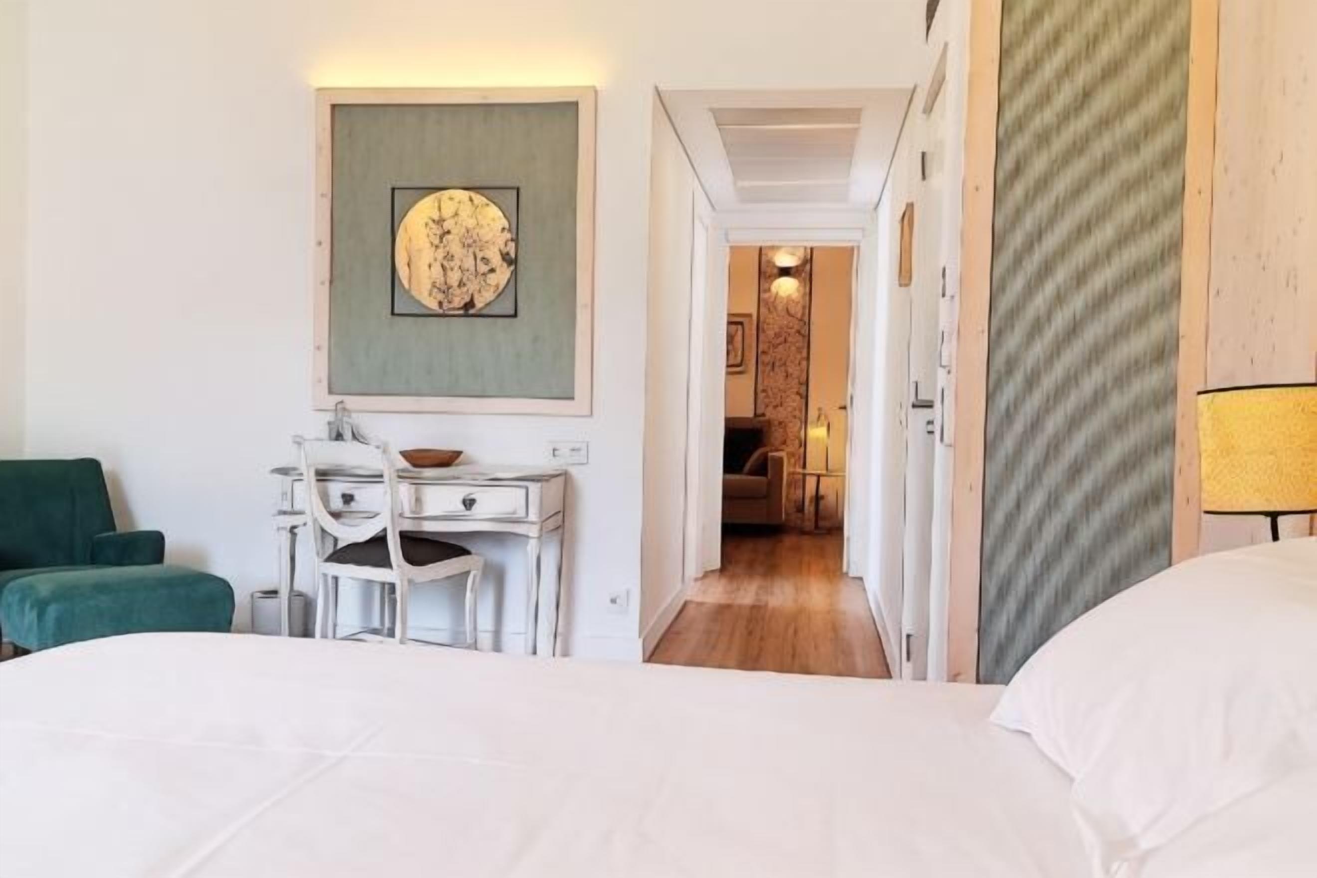 Una habitación de hotel con cama, escritorio, silla y un cuadro en la pared.