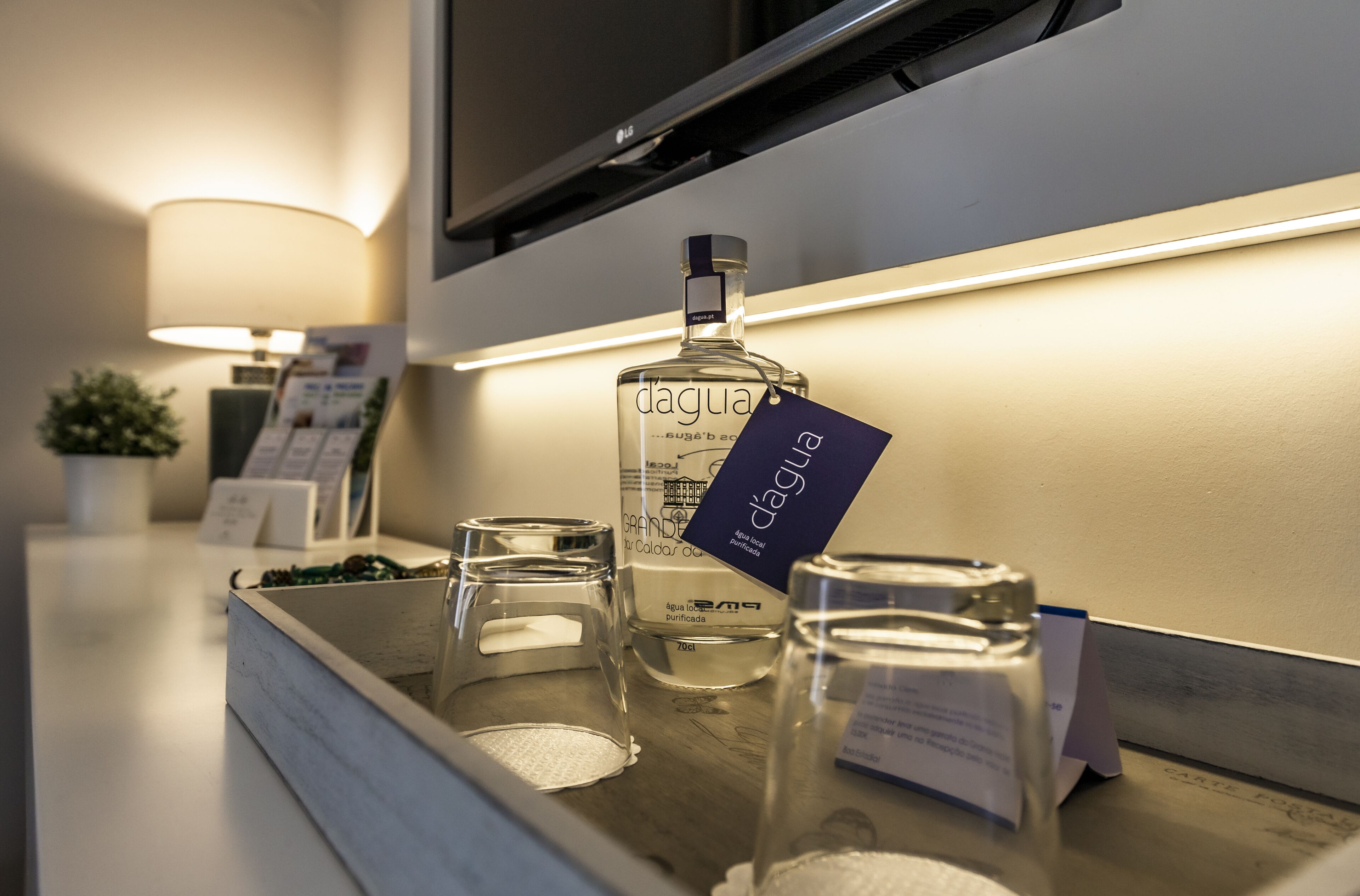 A minibar with a bottle of 'dagua' liquor, a glass, and a candle on a hotel counter.