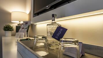 Een minibars met een fles 'dagua' drank, een glas en een kaars op een hotelbar.