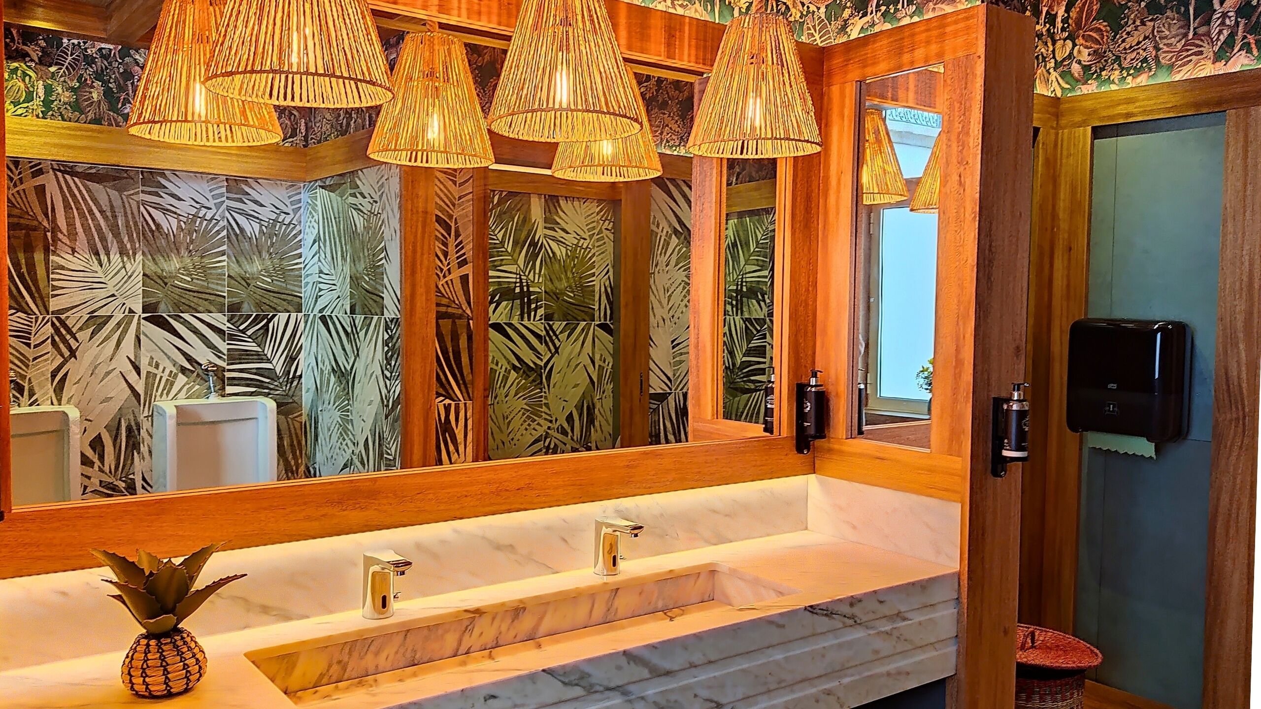 Un baño con un espejo grande, tocador de madera y una decoración con piña.
