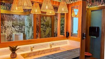 Un baño con un espejo grande, tocador de madera y una decoración con piña.