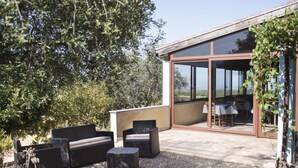 A modern outdoor seating area with a glass door leading to a dining space.