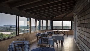 A restaurant with outdoor seating, large windows, and a view of the countryside.