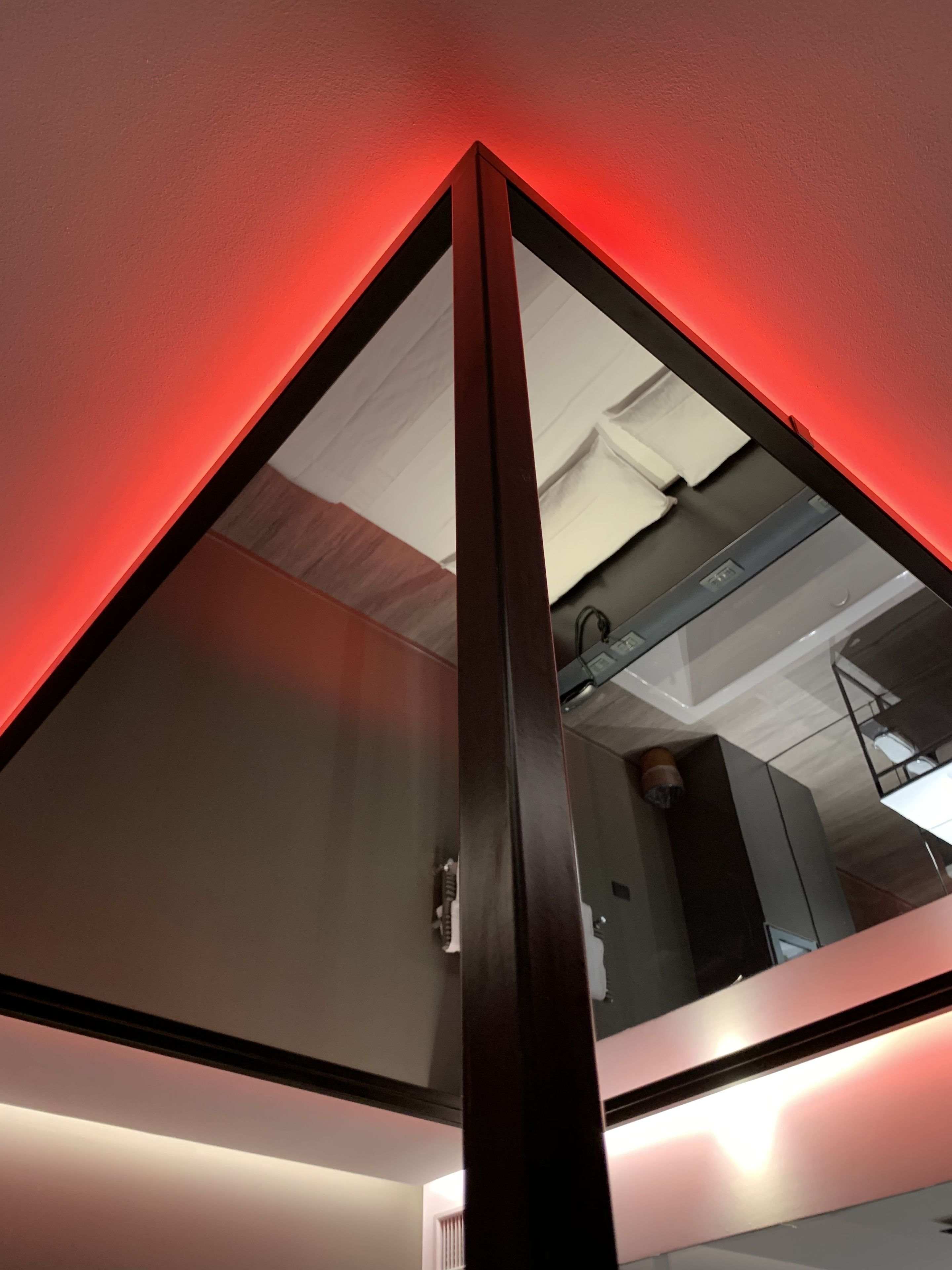 A modern interior with a red-lit ceiling, a glass partition, and a visible ceiling duct.