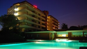 A multi-story hotel with a swimming pool, balconies, and a well-lit exterior. - Hotel Terme Imperial (Montegrotto Terme)