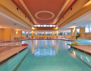 A large indoor swimming pool with multiple lanes, sun loungers, and a waterfall feature. - Hotel Terme Imperial (Montegrotto Terme)