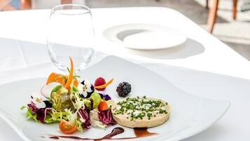 A white table with a plate of food, a glass of water, and a white plate.