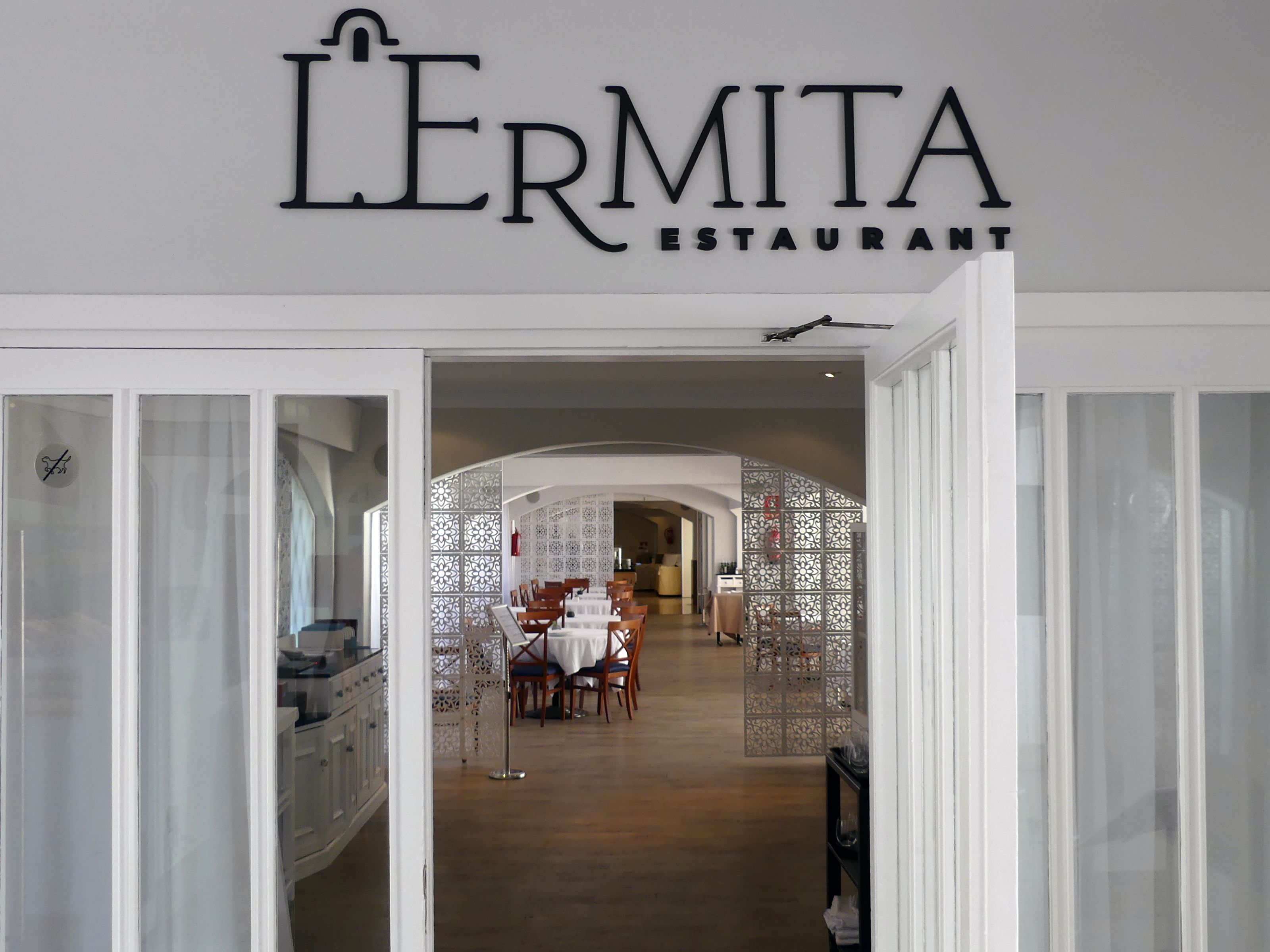 La entrada al restaurante LERMITA, con una decoración moderna y vistas al comedor.