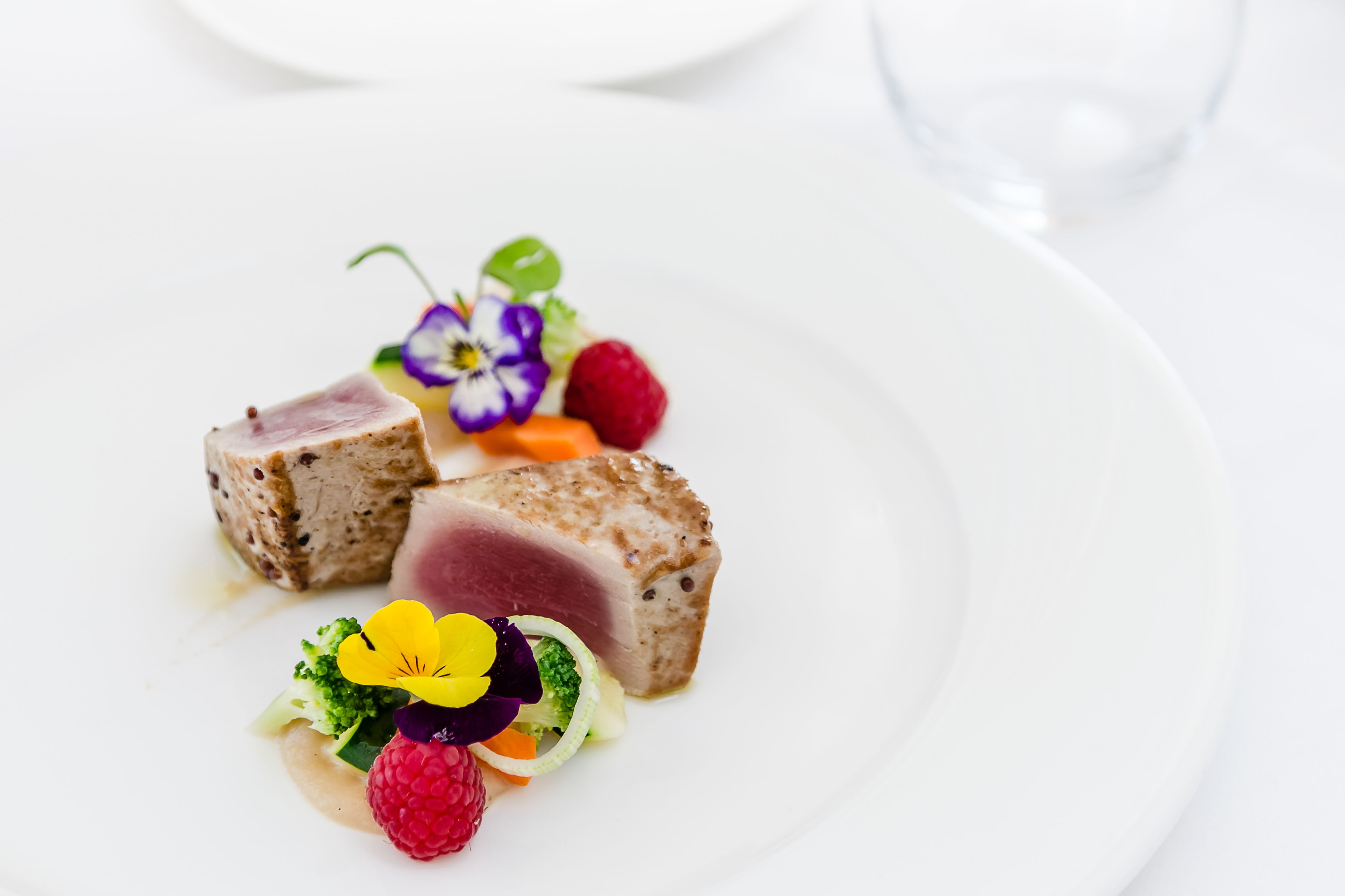 A white plate with a dish of food, including a piece of meat and some vegetables.