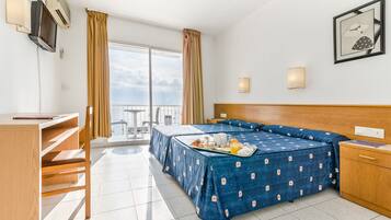 A hotel room with a bed, a desk, a chair, a TV, and a balcony with a view.