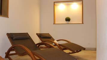 Een kamer met drie houten lounge fauteuils en een wandlamp.