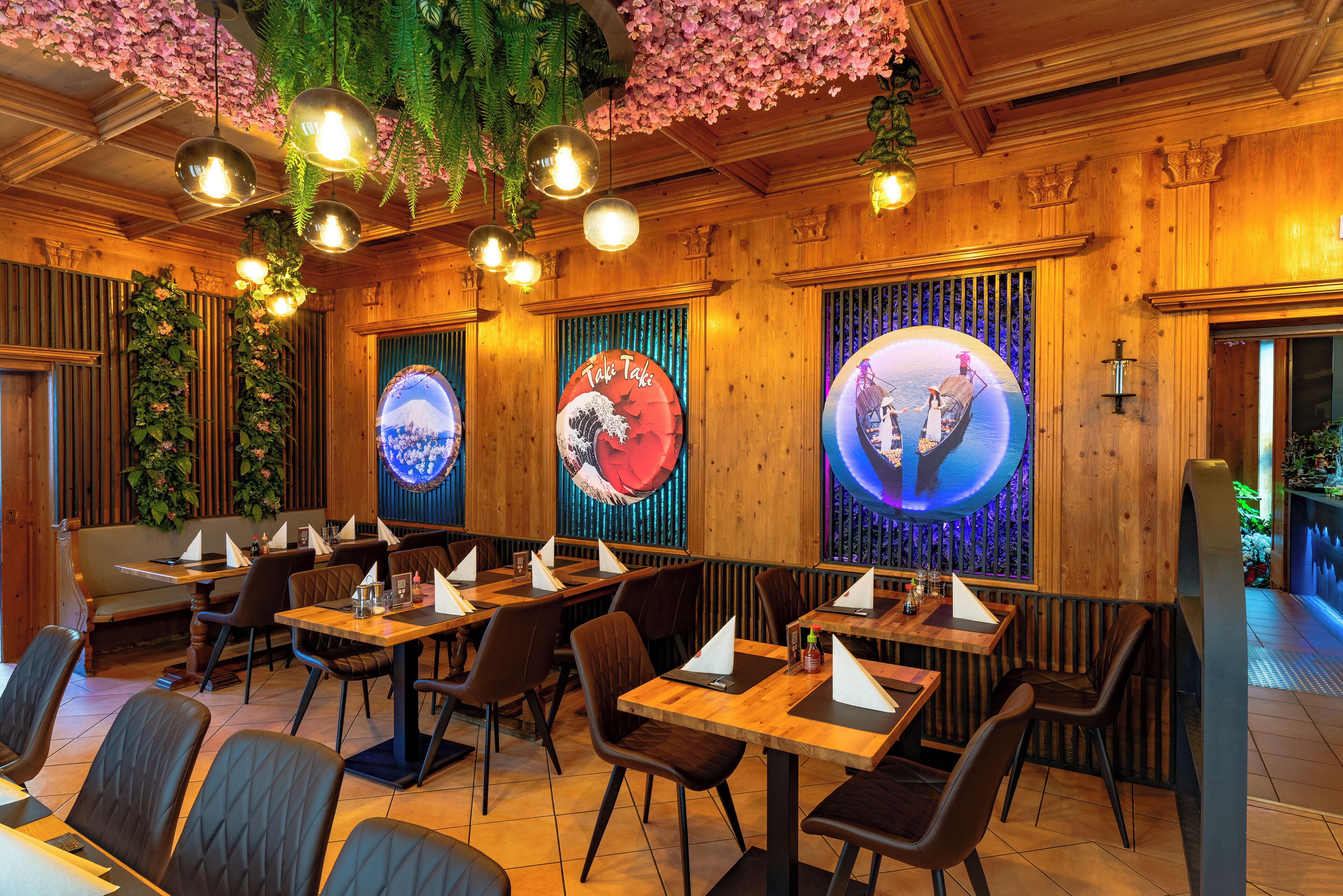 Un restaurante con paredes de madera, plantas colgantes y letreros iluminados.
