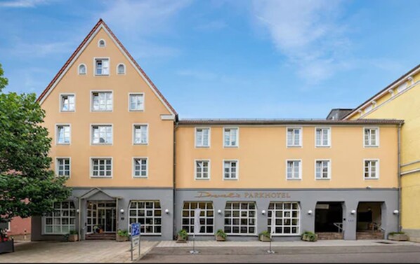 Un hotel de estilo arquitectónico europeo tradicional, con una fachada simétrica, varios ventanales y una entrada central.