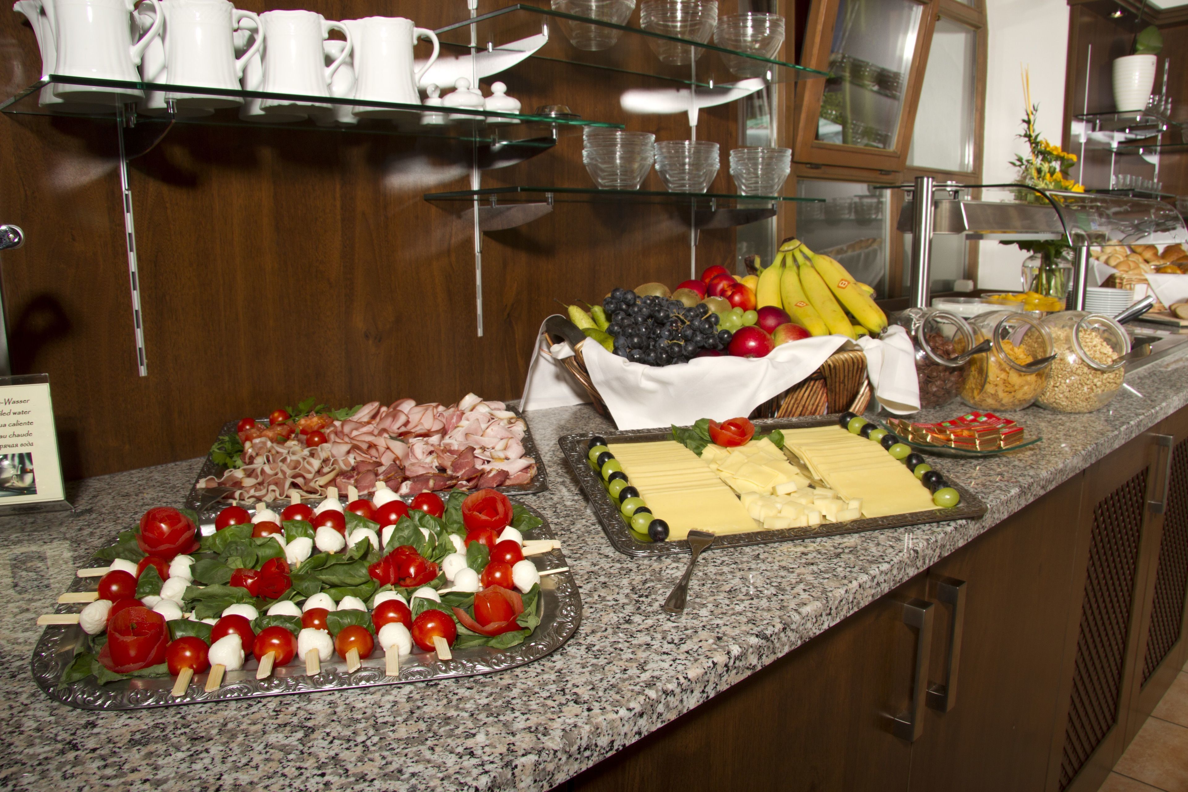 Een buffet met diverse gerechten, waaronder vlees, kaas, fruit en groenten.