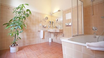 A bathroom with a bathtub, a sink, a mirror, and a potted plant.