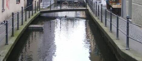 A narrow canal flanked by buildings with balconies and a bridge in the distance.