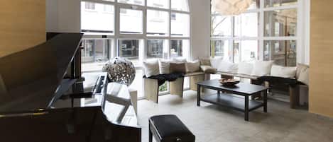 Amplia sala de estar con piano, ventana grande y una lámpara moderna.