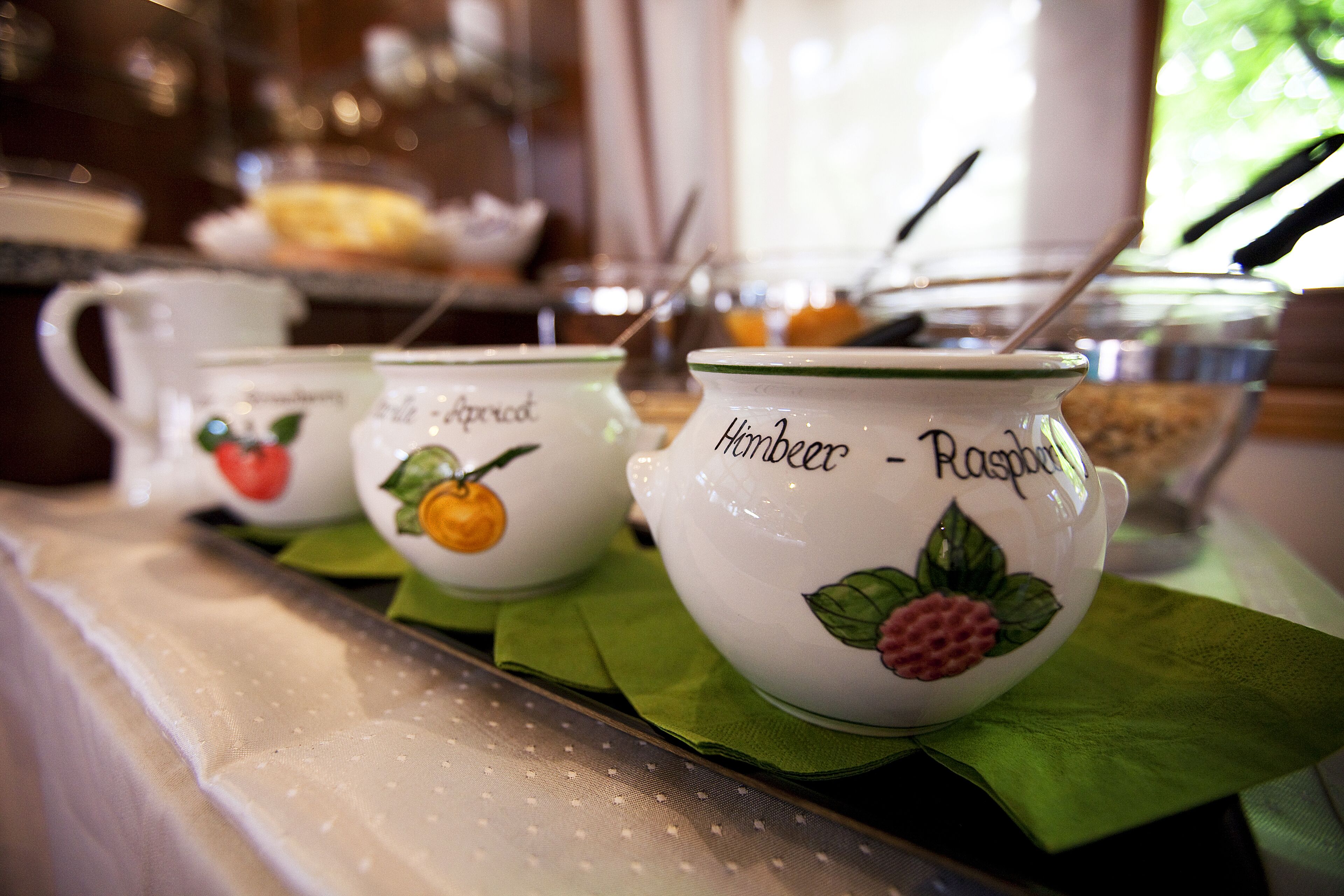 A row of ceramic cups with fruit designs and names on a table.