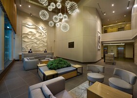 A modern lobby with a reception desk, seating area, and a staircase.