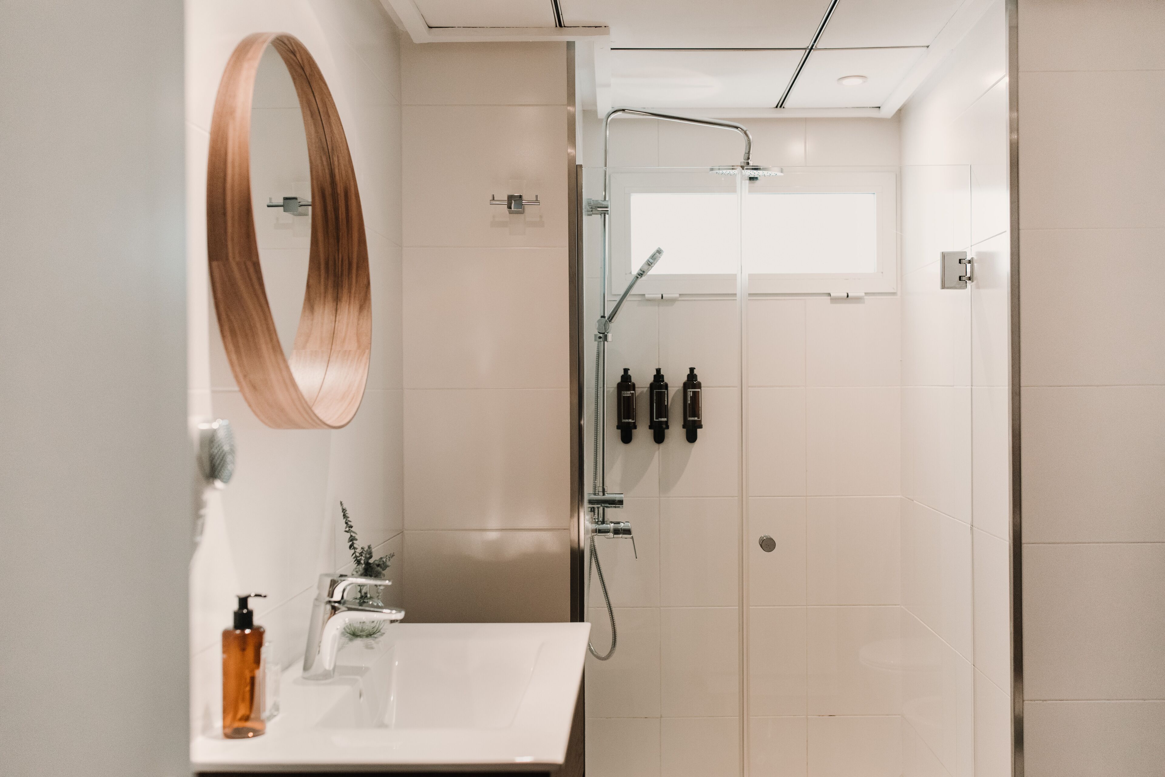 A modern bathroom with a large mirror, a shower, and a sink.