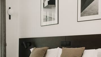 A neatly made bed with a black headboard, two pillows, and a camera on the bed.
