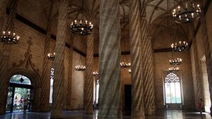 Un intérieur spacieux avec de hauts plafonds en voûte et de grandes colonnes, agrémenté de nombreux lustres et d’une grande fenêtre à vitraux.