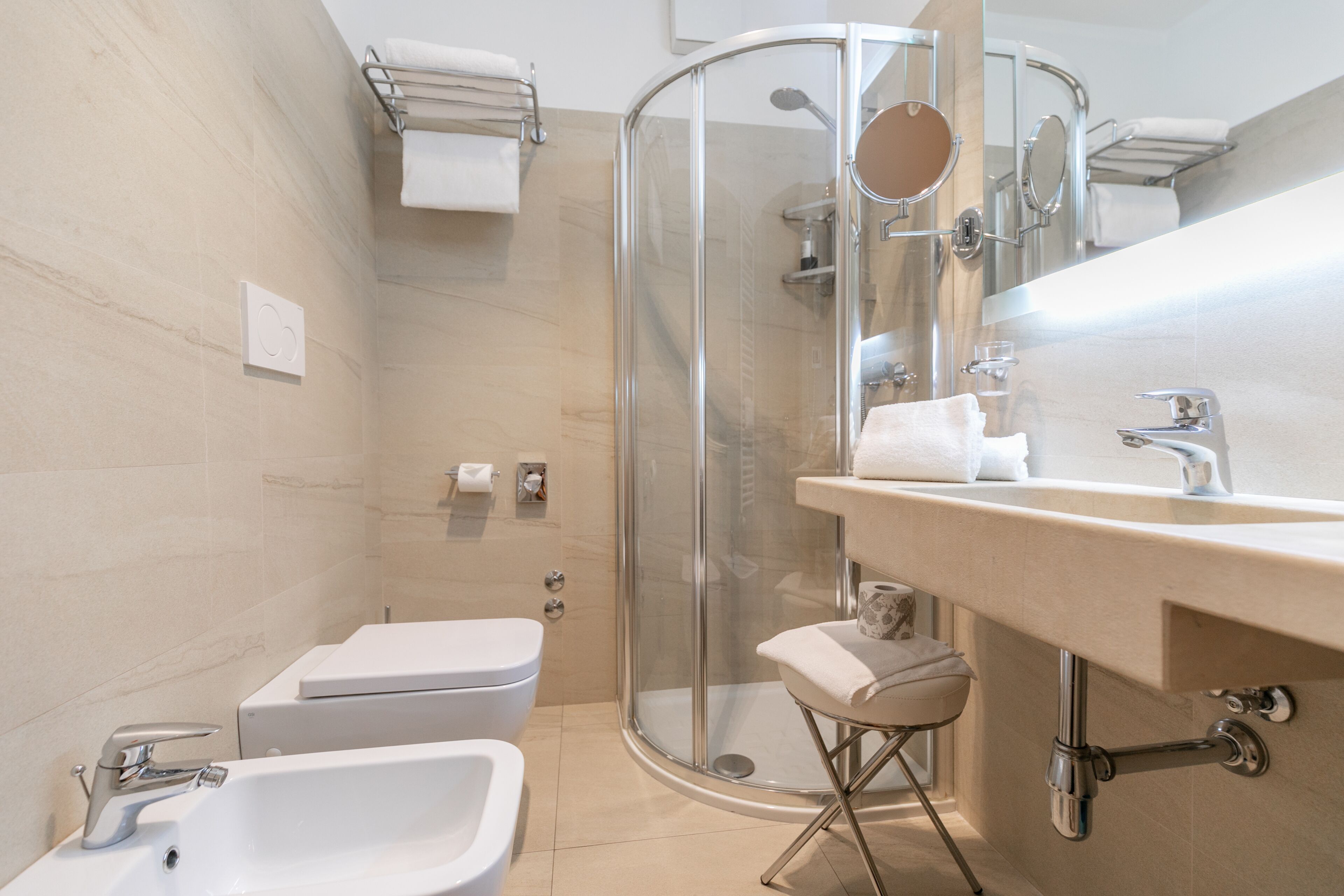 A modern bathroom with a glass shower enclosure, a bidet, a sink with a vanity, and a toilet.