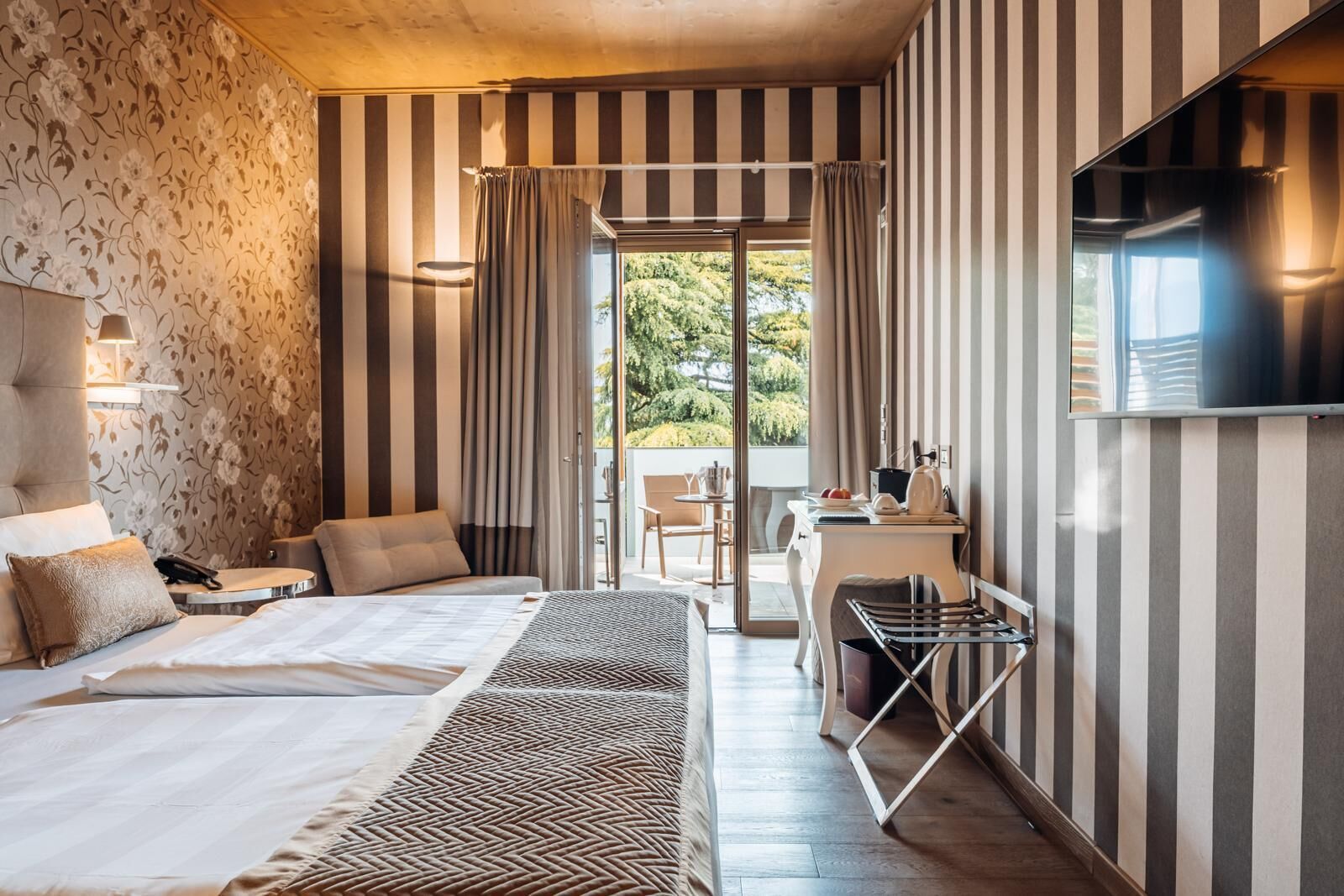 A hotel room with a bed, a desk, a chair, and a TV.