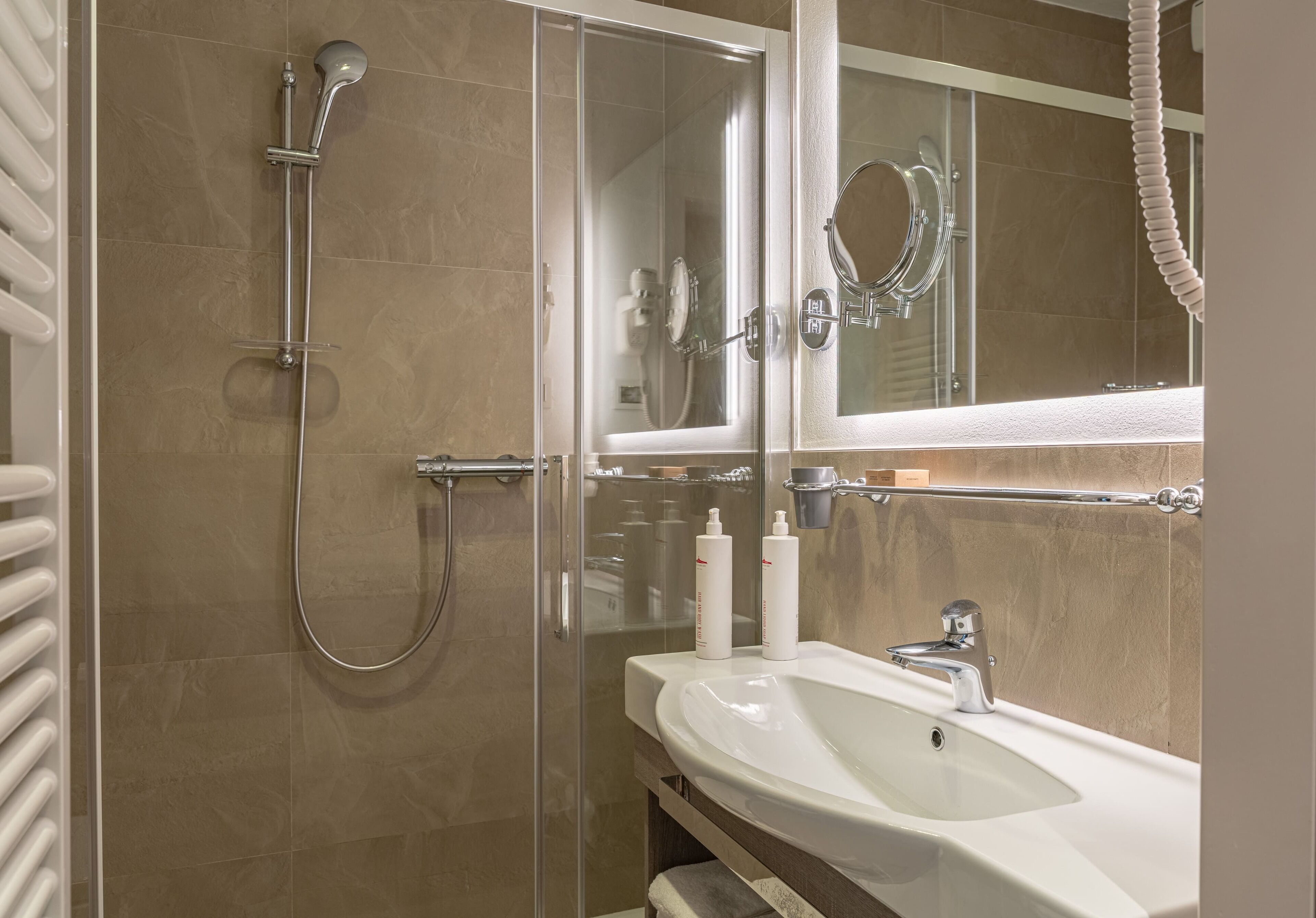 A modern bathroom with a glass shower enclosure, a white sink, and a mirror above the sink.