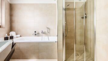 Un baño moderno con ducha acristalada, bañera y tocador con artículos de aseo.