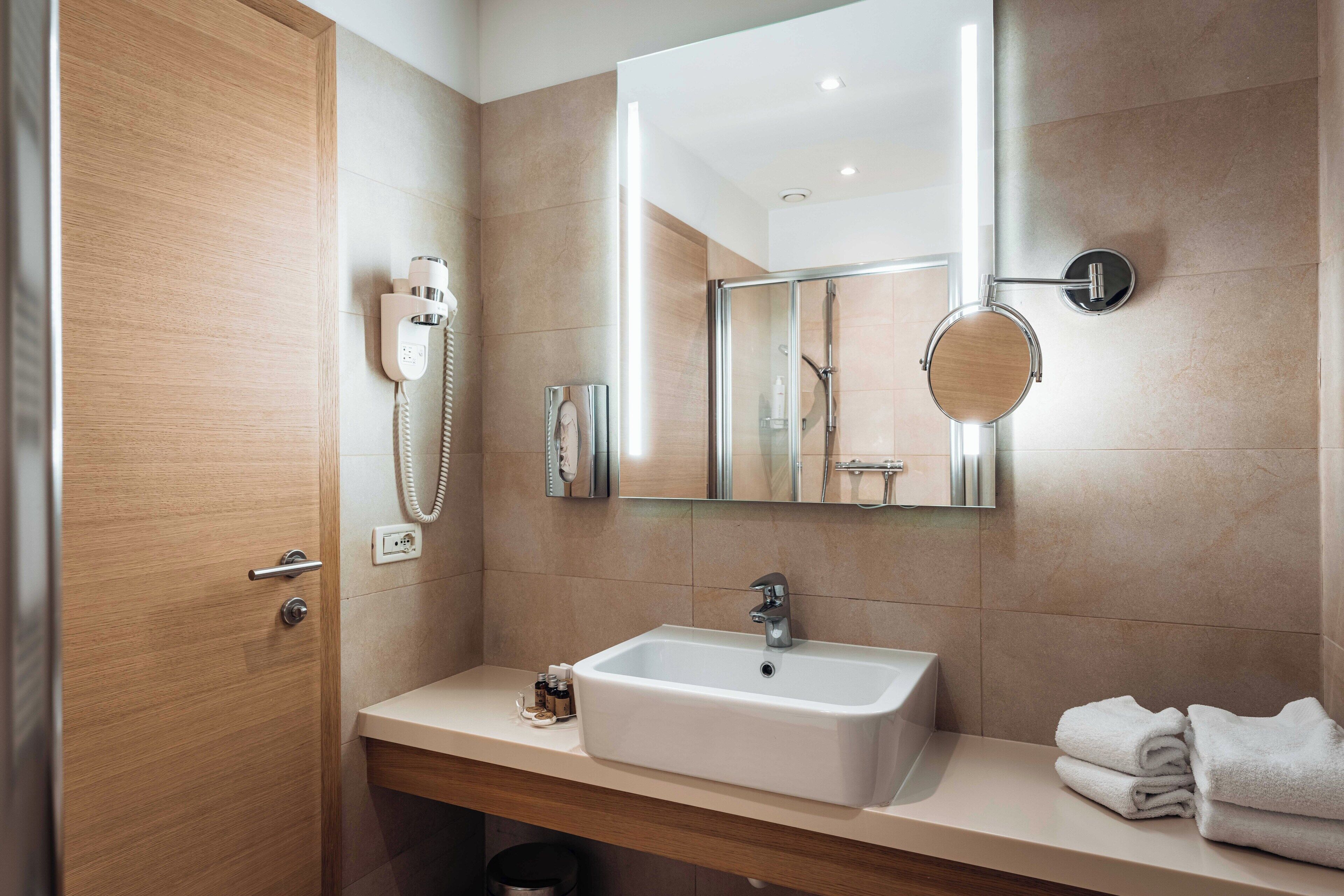 Un baño moderno con un espejo grande, un lavabo y un perchero para toallas.