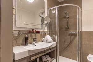 Un baño moderno con ducha de vidrio, un lavamanos blanco y un espejo encima.