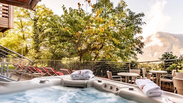 A hot tub with towels, surrounded by outdoor seating and trees. - Villa Madruzzo (Trento)