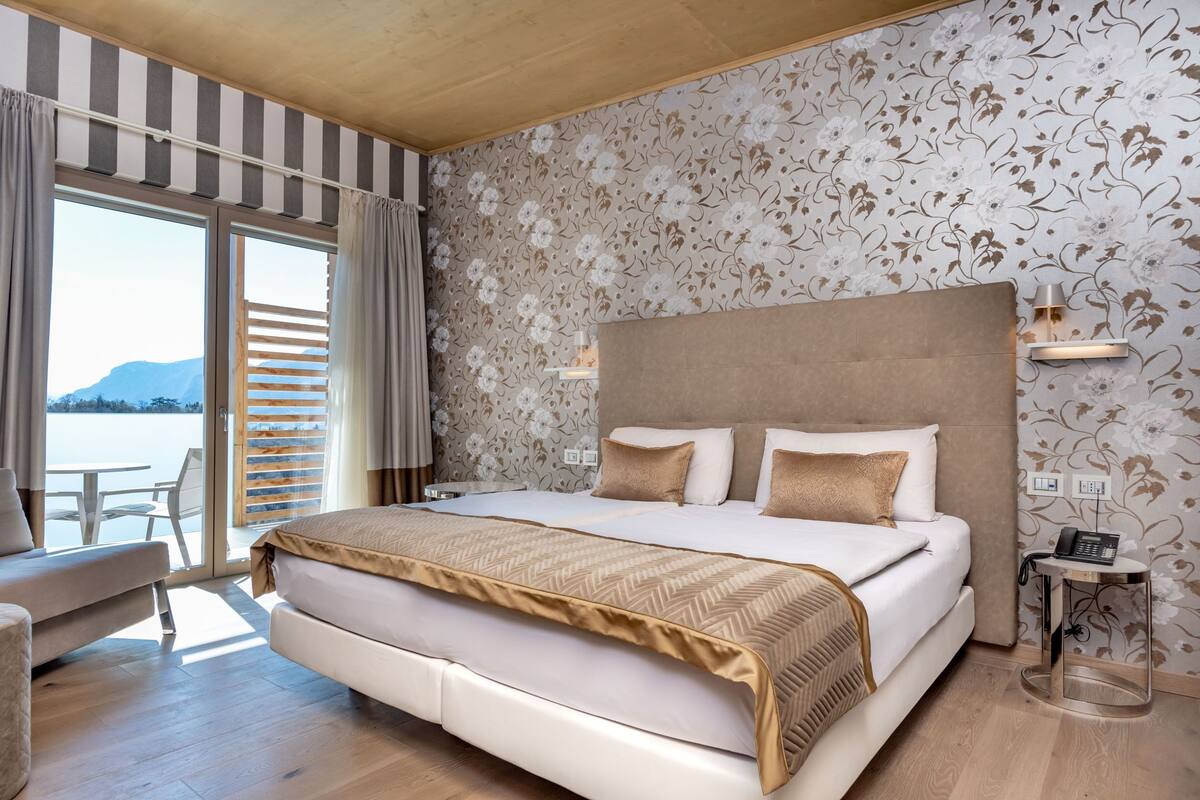 Ein modernes Hotelzimmer mit einem großen Bett, einer Couch, einem kleinen Tisch und Blick aufs Meer.