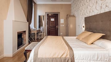 Una habitación de hotel con una cama grande, una chimenea, un escritorio y un armario.