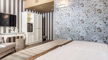 Ein Hotelzimmer mit Bett, Fernseher, Schreibtisch und Kleiderschrank.