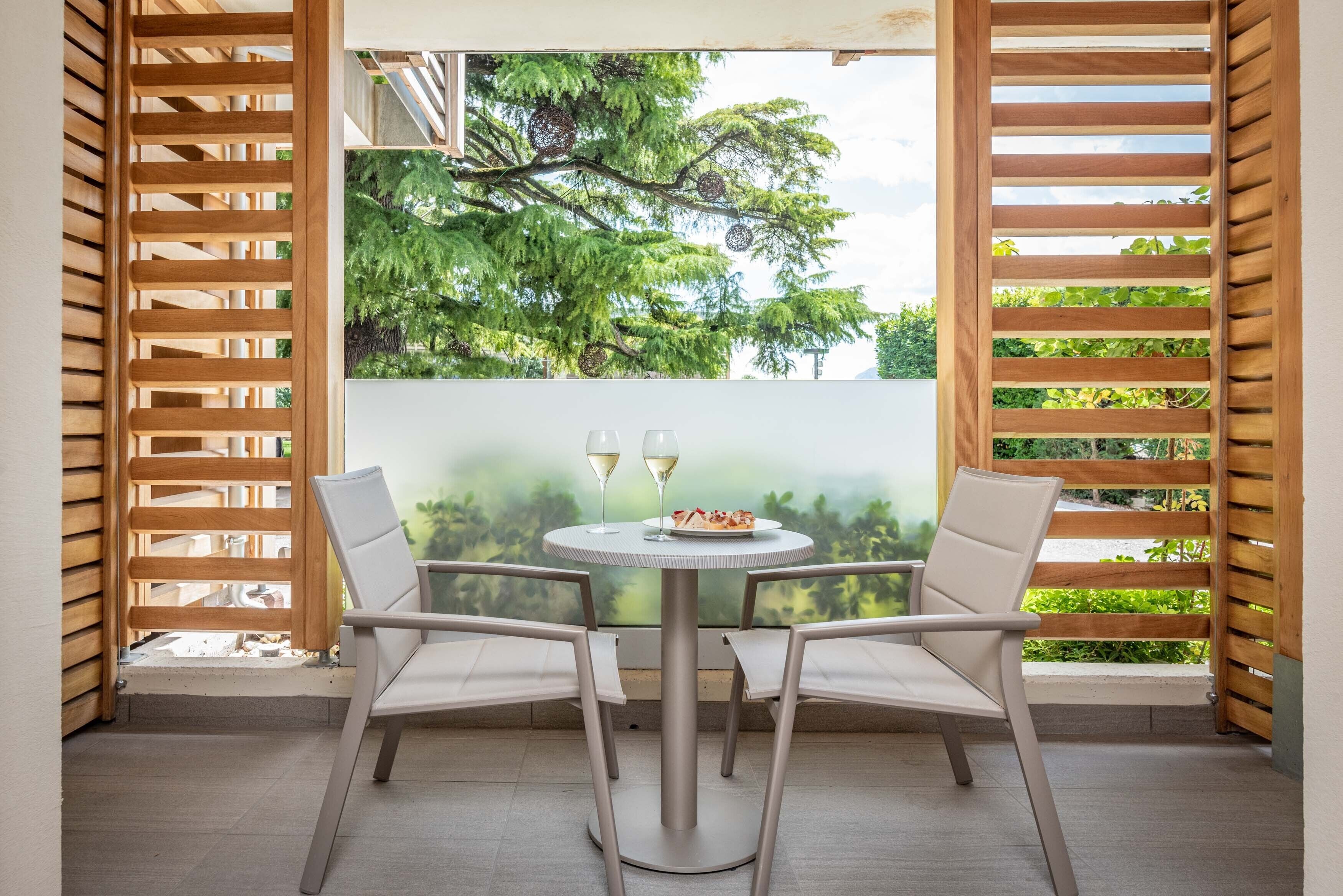 A patio with a round table, two chairs, and two glasses of white wine.