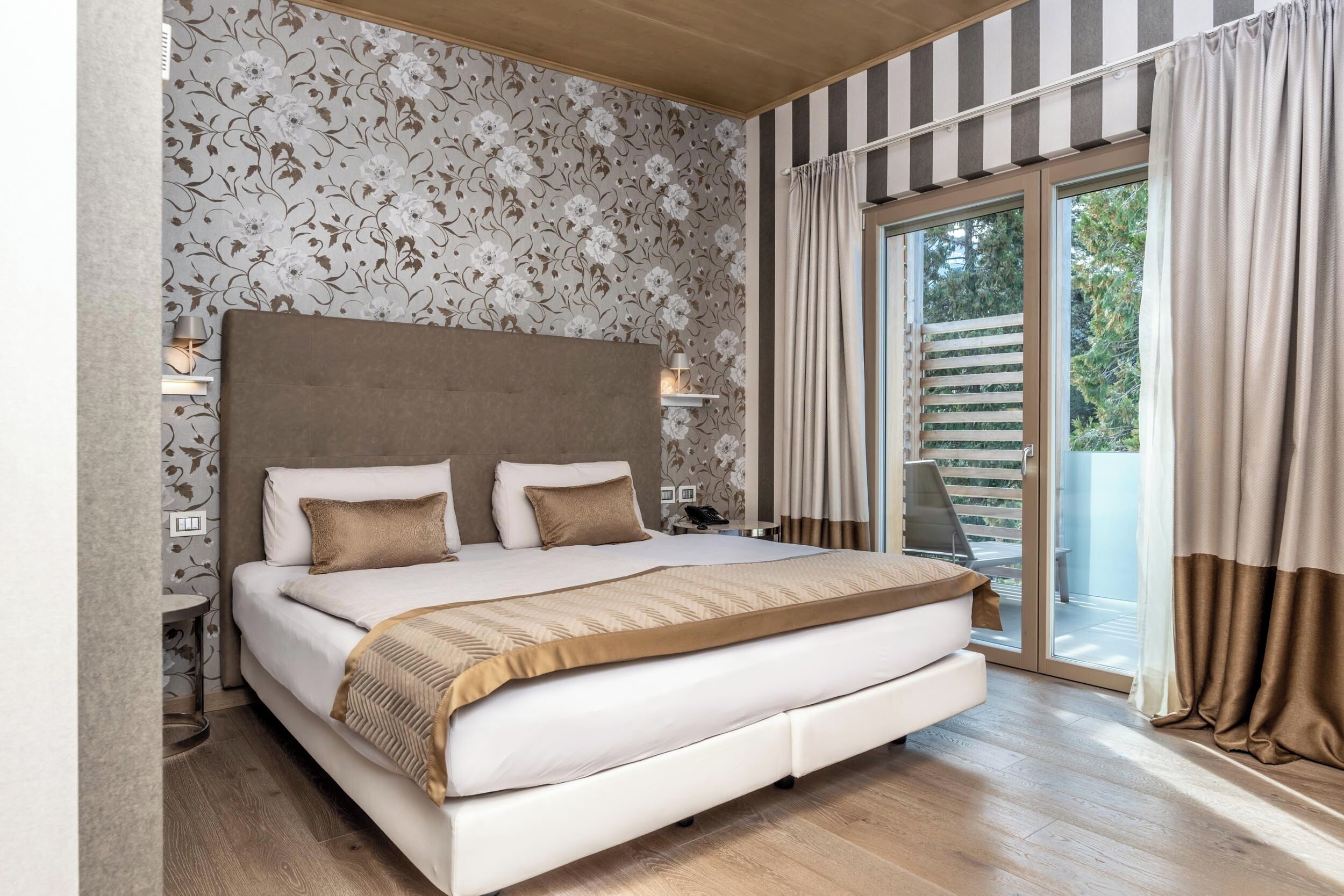 A large bed with a headboard, bedside tables, and a view of the outdoors through a sliding glass door.