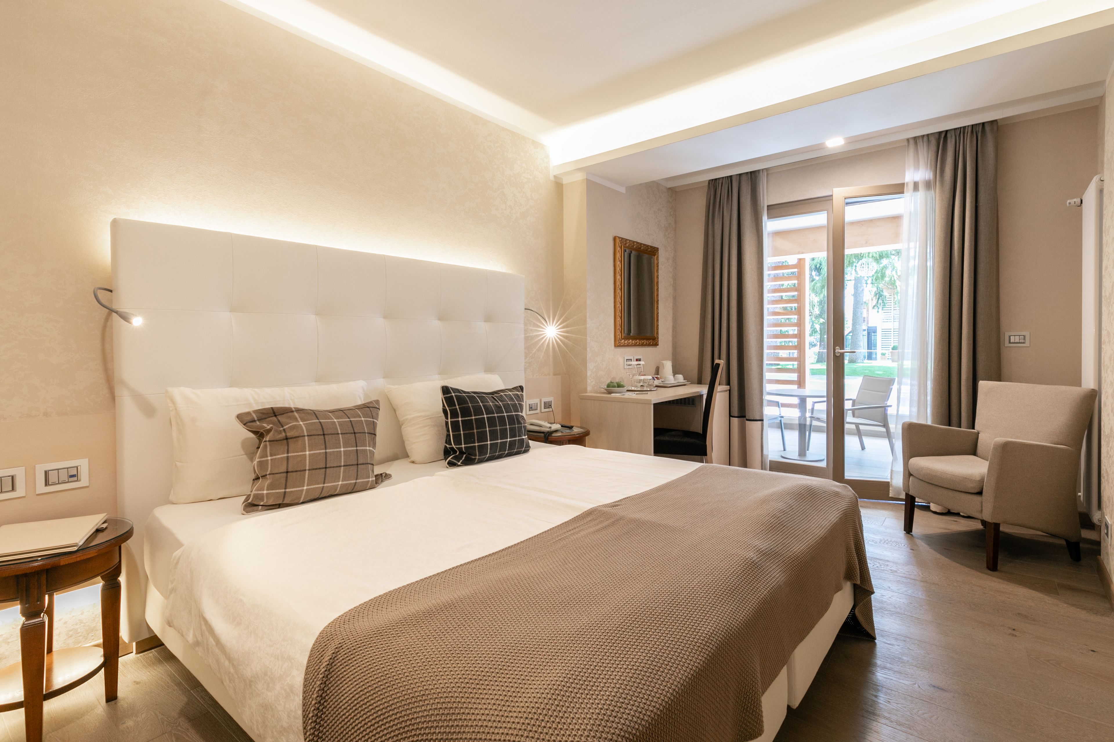 Une chambre d’hôtel avec un grand lit, un bureau, une chaise et un balcon avec des rideaux.