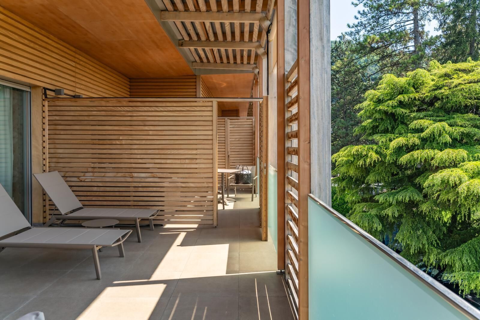 A modern outdoor seating area with wooden slats and a view of lush greenery.