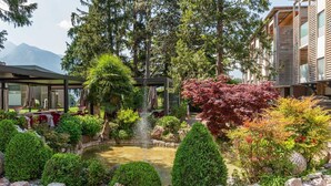 A landscaped garden with a fountain, neatly trimmed bushes, and a paved walkway. - Villa Madruzzo (Trento)