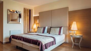 Habitación de hotel con una cama grande, dos mesitas de noche con lámparas, un espejo y un cabecero de madera.