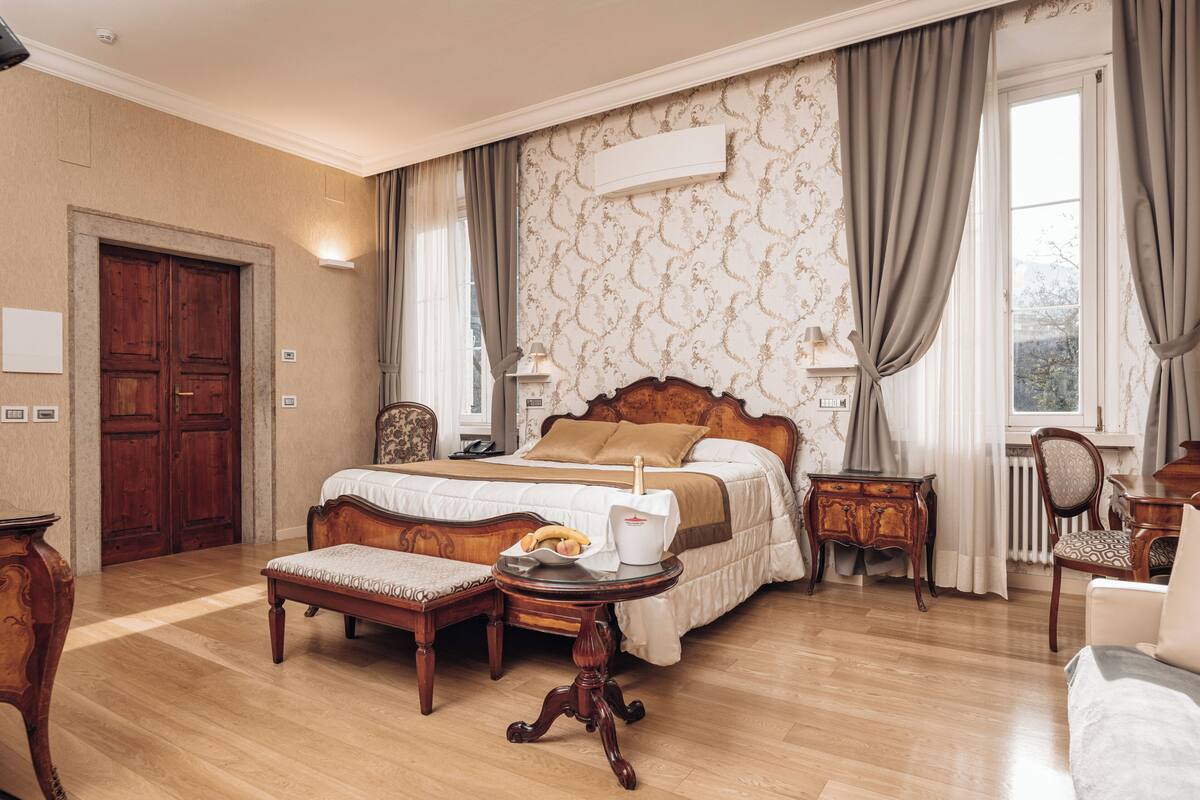 Ein geräumiges Schlafzimmer mit einem großen Bett, Holzmöbeln und Blick ins Freie.