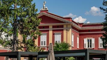 Un edificio rosso con persiane bianche e una statua sul tetto.