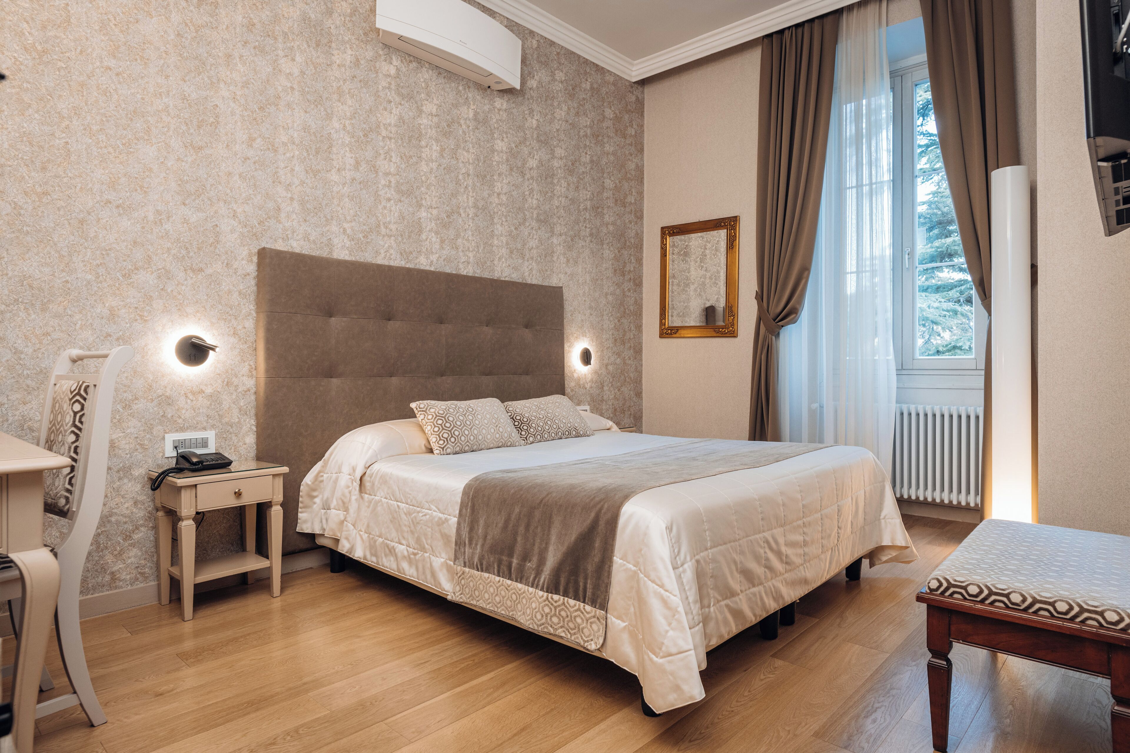 Una camera da letto con un letto grande, comodini, una sedia e una finestra con tende.