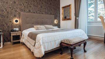 Une chambre à coucher avec un grand lit, des tables de chevet, une commode, un banc, un miroir et une fenêtre avec des rideaux.